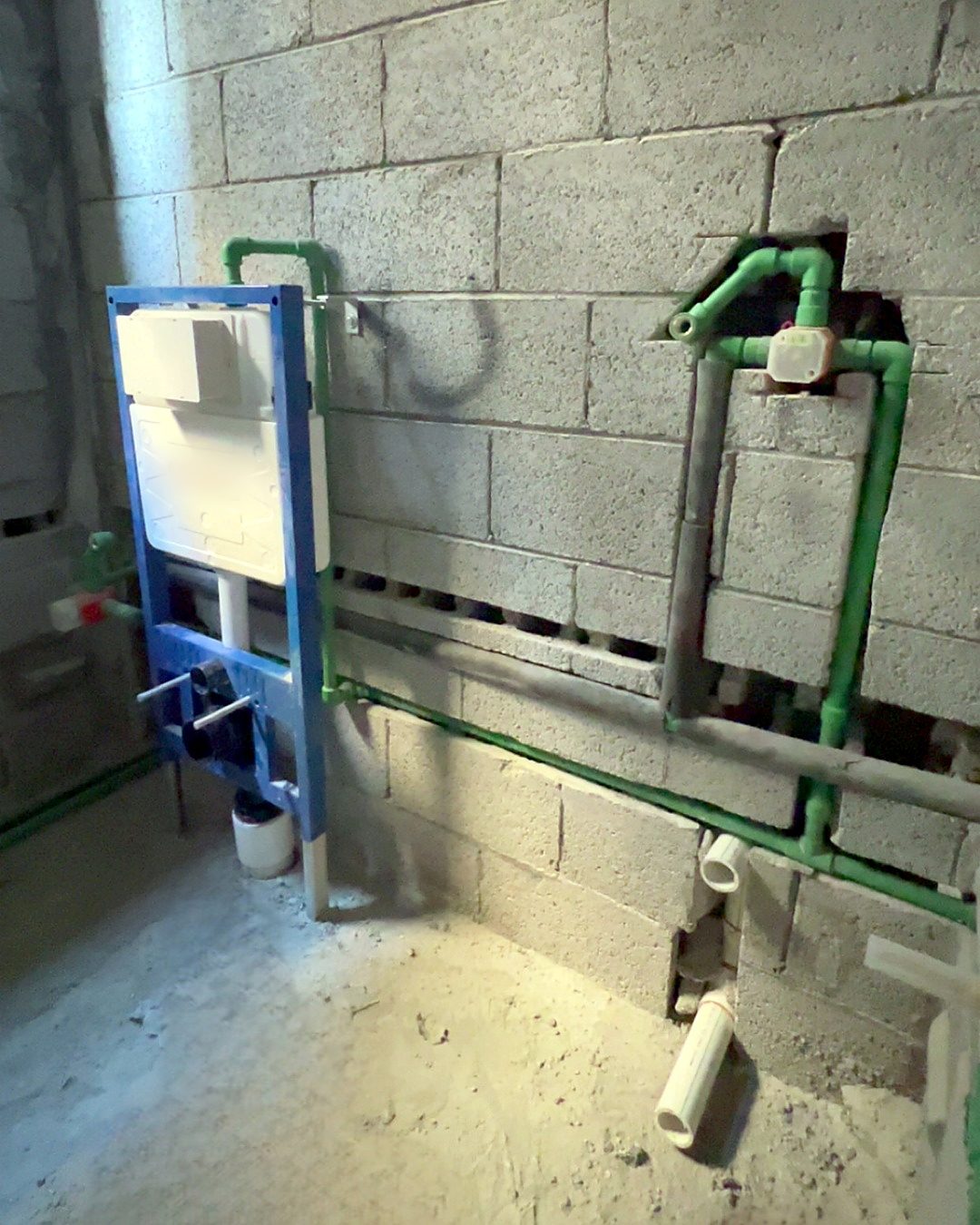 A concealed cistern frame fixed on a block wall with green water lines, before covering