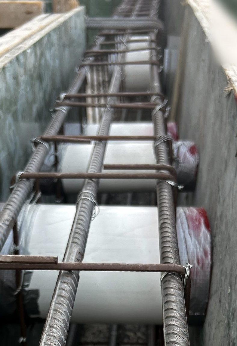 White pipes with red caps inside a rebar cage before pouring